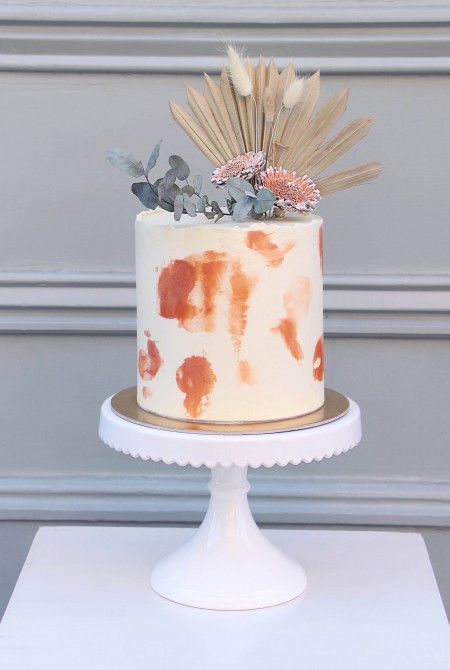 Sötét naranccsal dekorált torta fehércsoki burkolással